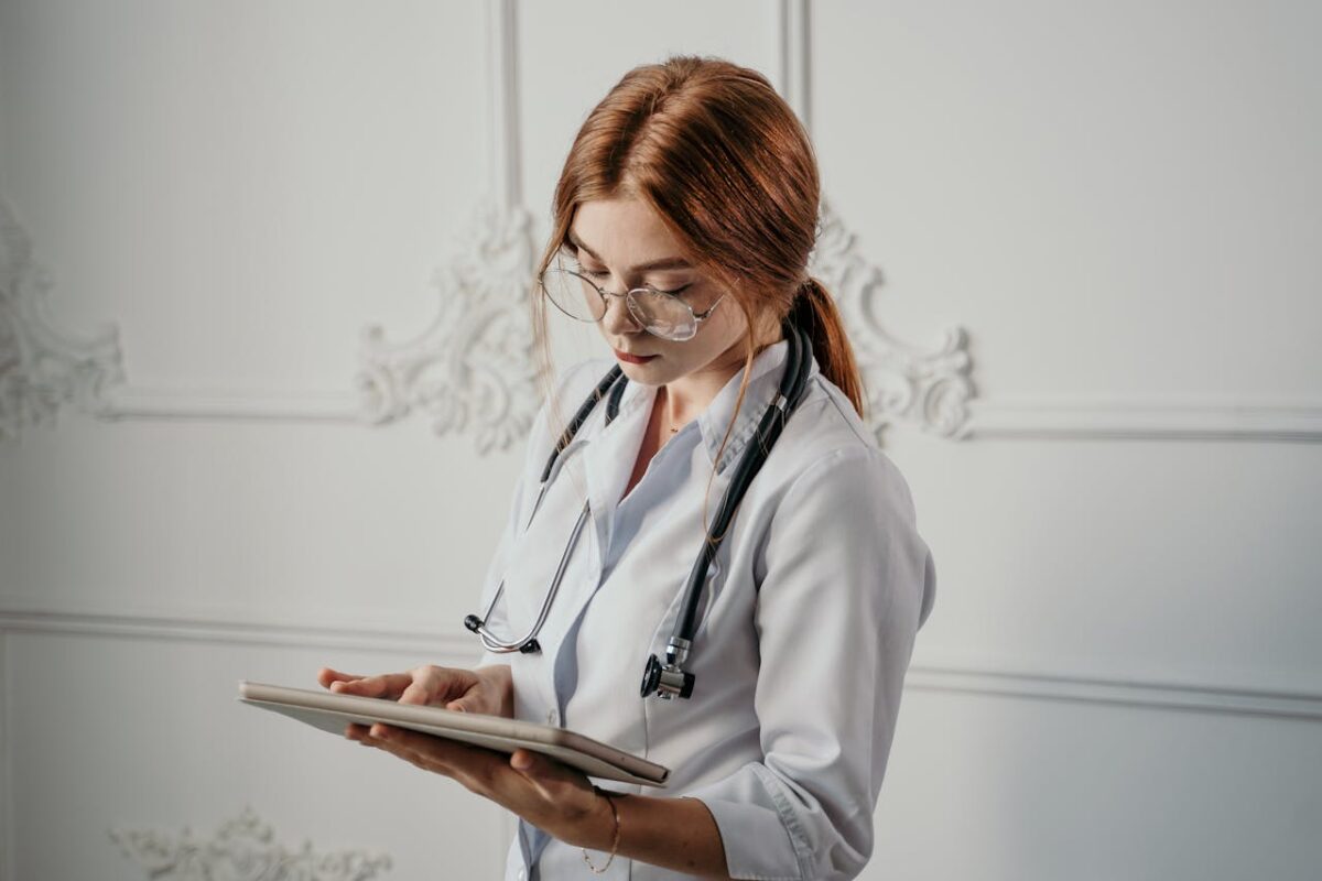 Female doctor in white coat using a tablet, emphasizing modern healthcare and technology.