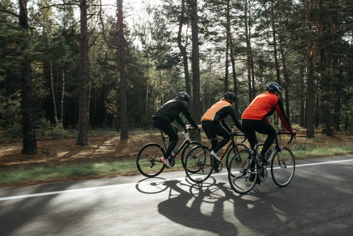 Three cyclists riding on a forest road, showcasing outdoor sports and fitness lifestyle.